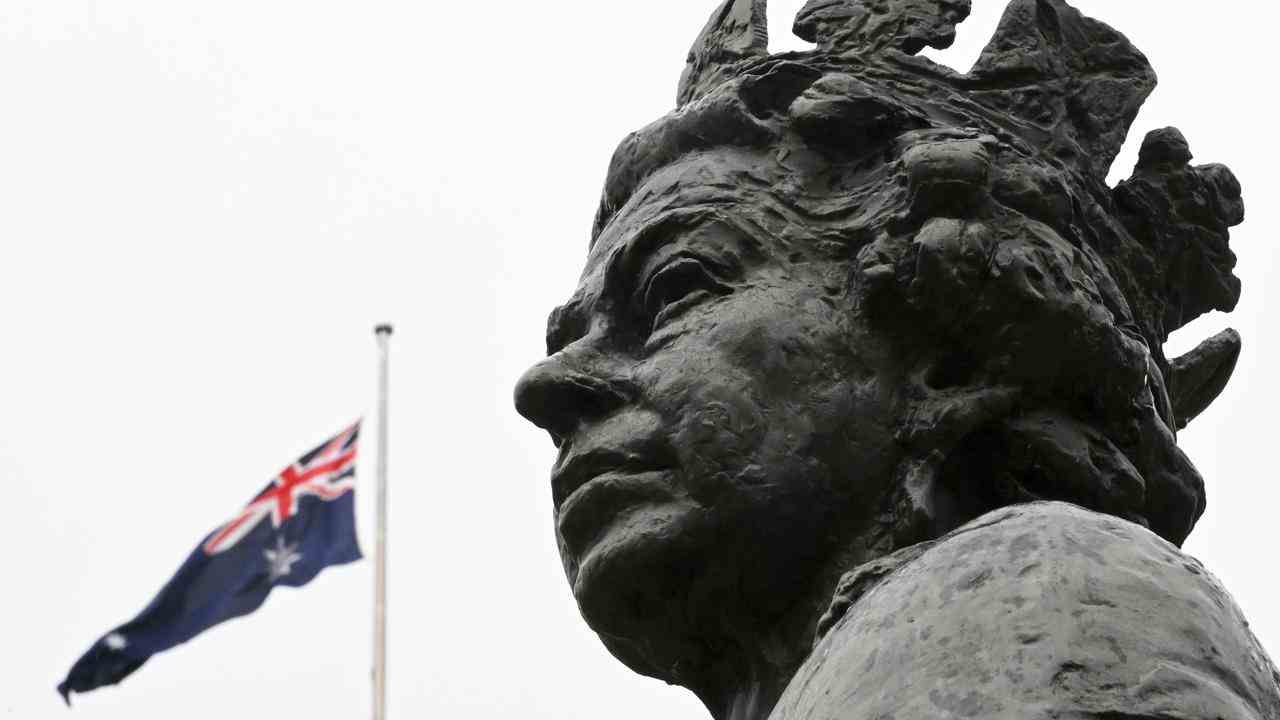 Die australische Flagge auf Halbmast hinter einer Statue Ihrer Majestät der Königin im Parlamentsgebäude in Canberra, Australien