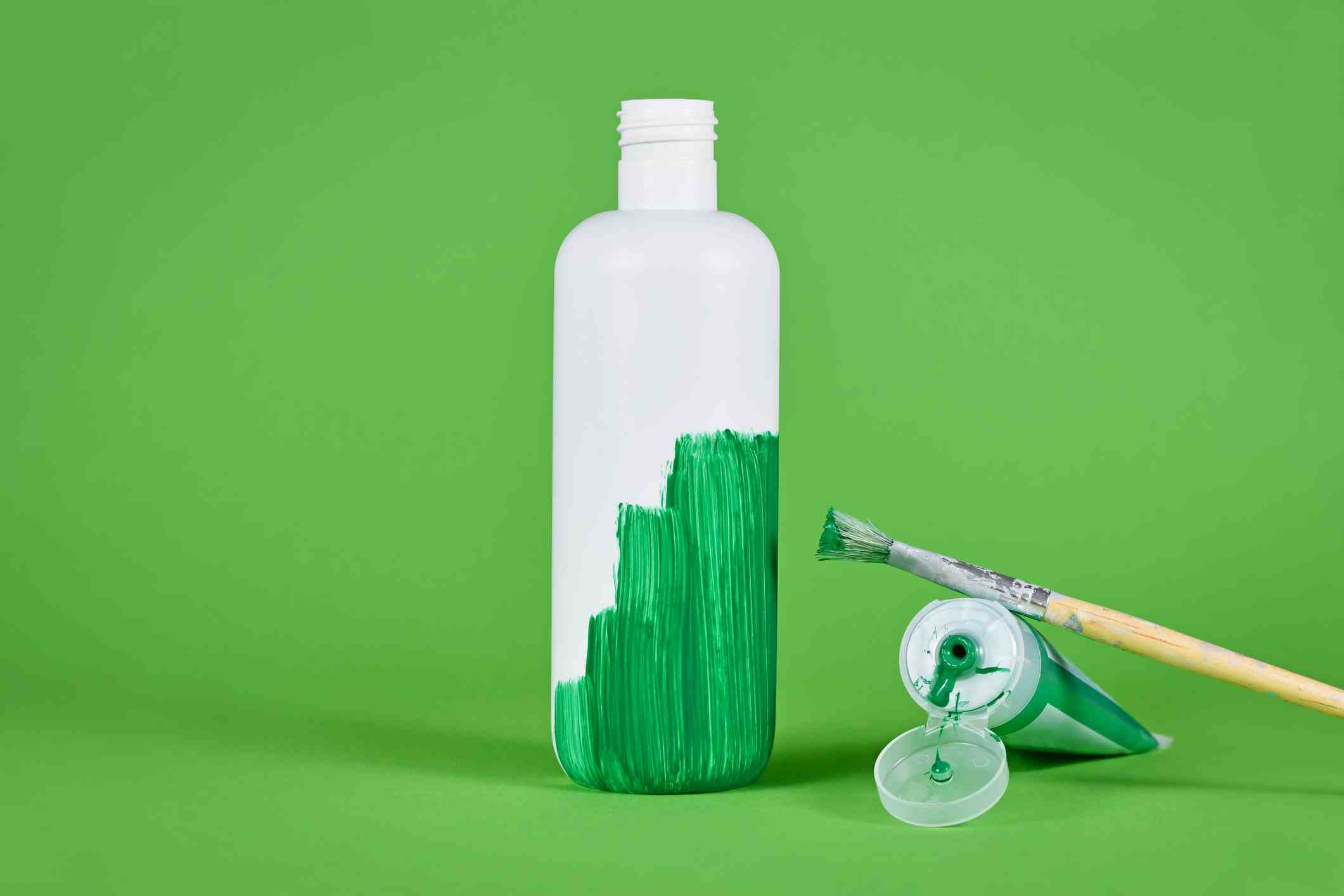 Weiße Plastikflasche, die grün gestrichen wird;  Greenwashing