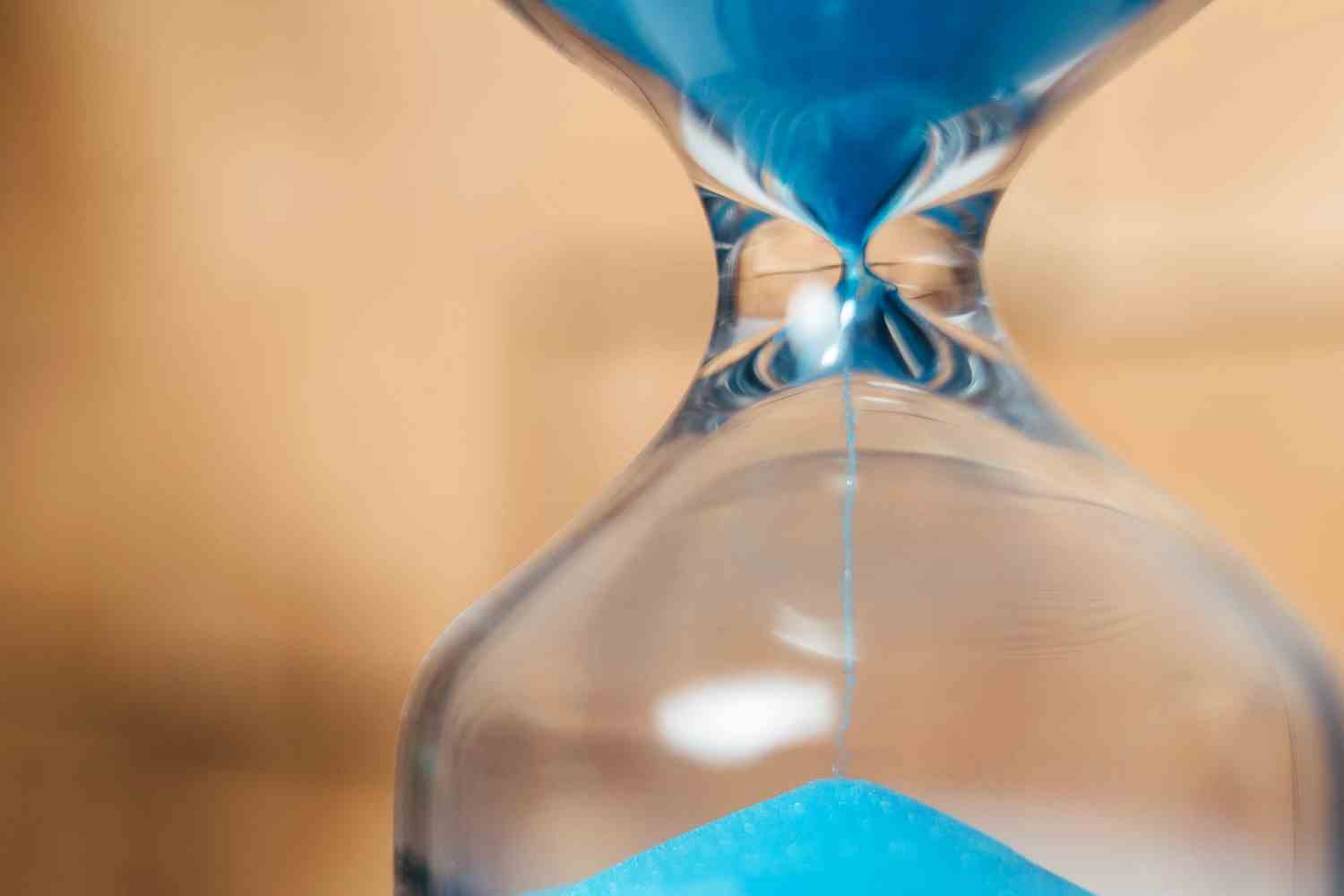 Nahaufnahme des blauen Sandes, der in die Sanduhr fällt