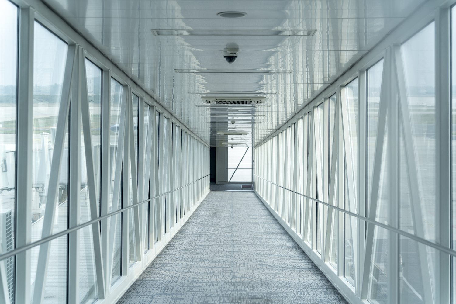 Eine perspektivische Aufnahme mit Blick auf den Korridor einer Fluggastbrücke an einem Flughafen