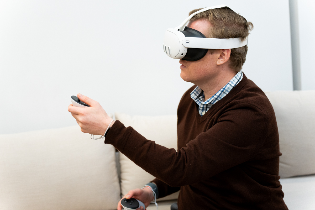 Mann mit dem Meta Quest 3 Mixed-Reality-Headset und einem Controller in der Hand, von der Seite betrachtet