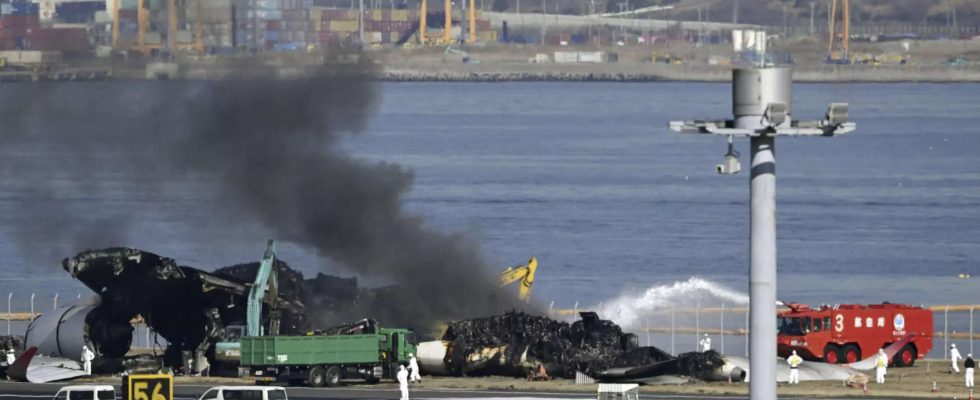 Japanische Sicherheitsexperten suchen nach Sprachdaten waehrend Arbeiter Flugzeugtruemmer von einer