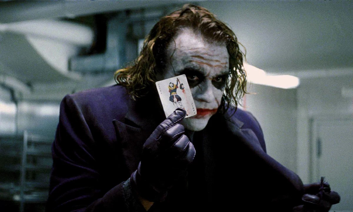 Heath Ledger als Joker, der im Dark Knight eine Jokerkarte hochhält