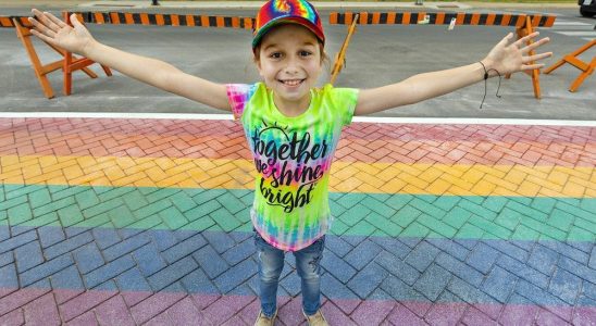 Young LGBTQ advocate beams with pride over rainbow crosswalk in