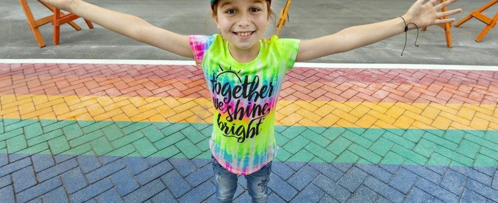 Young LGBTQ advocate beams with pride over rainbow crosswalk in