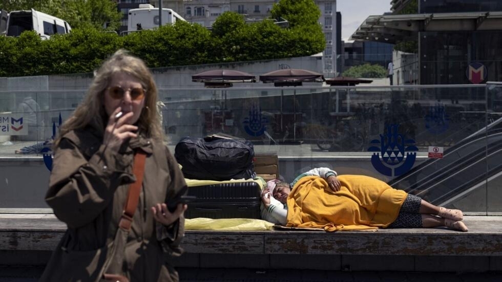 A homeless woman sleeps on a bench near Taksim Square in Istanbul on May 22, 2023.