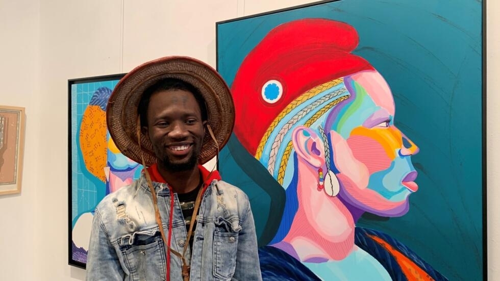 The painter Bella Bah poses proudly next to her painting, exhibited at the Sylvia Rielle gallery, in Paris, in October 2023.