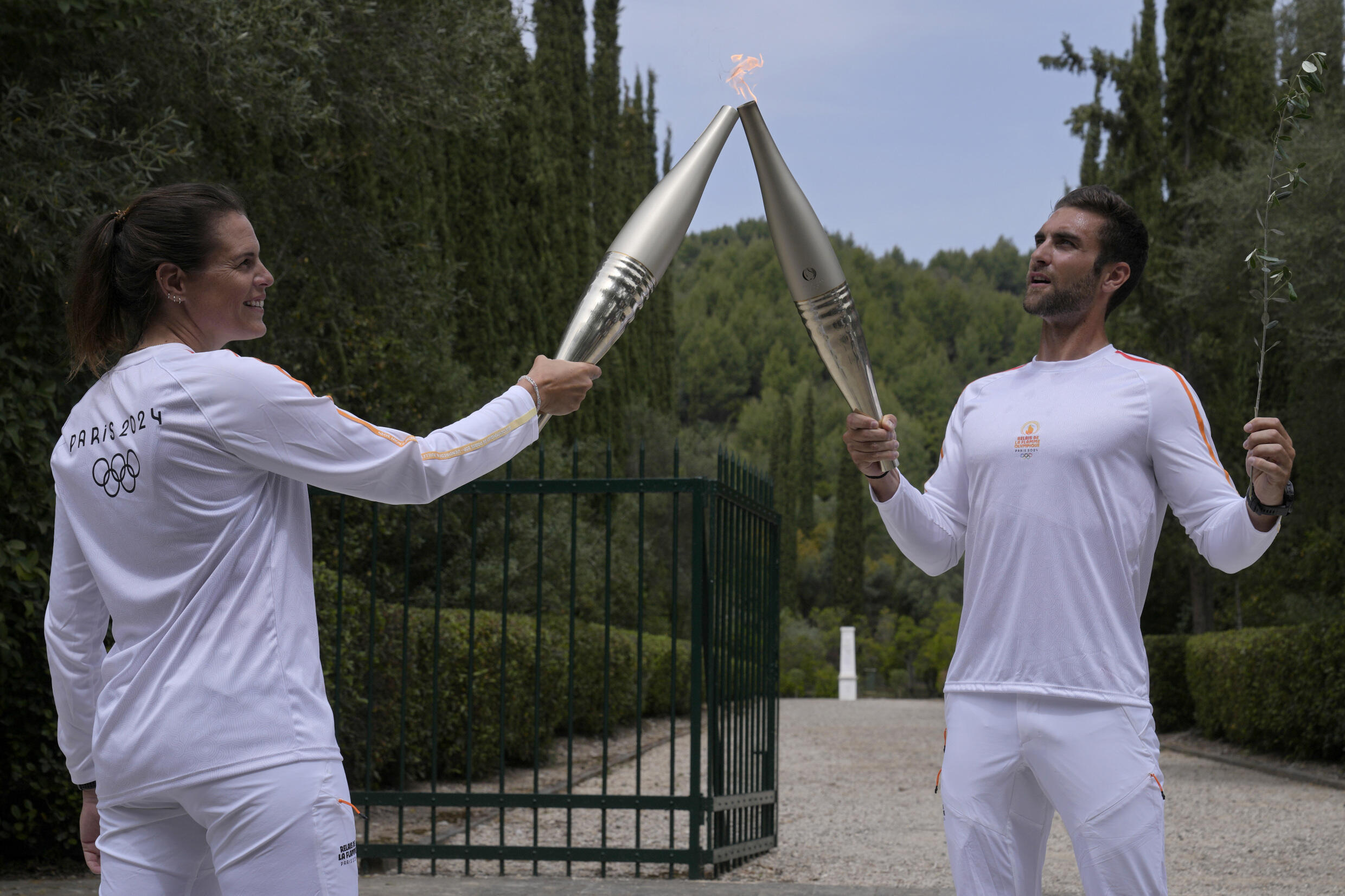 The first bearer of the Olympic flame, the Greek Stefanos Duskos (dr) passes the fire to the French champion, the swimmer Laure Manaudou, on April 16, 2024. 