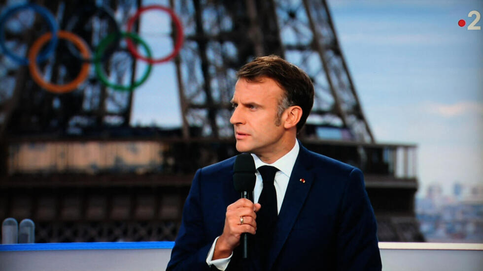 President Emmanuel Macron addressing a live interview on French TV on a set installed on the roof of the Musee de l'Homme at the Trocadero, Paris, with the Olympics rings seen in the background.