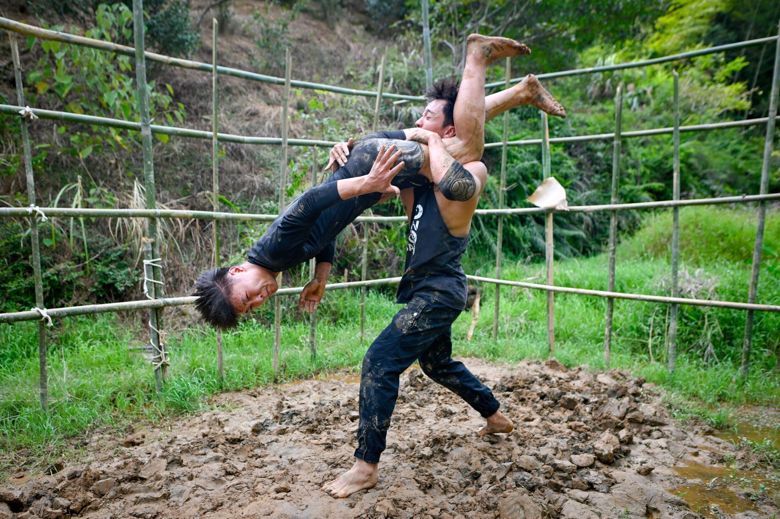 Wrestlers Wang Tao (L) and Chen Wenbin train in the mud in Xingning, south China's Guangdong province, September 12, 2024.